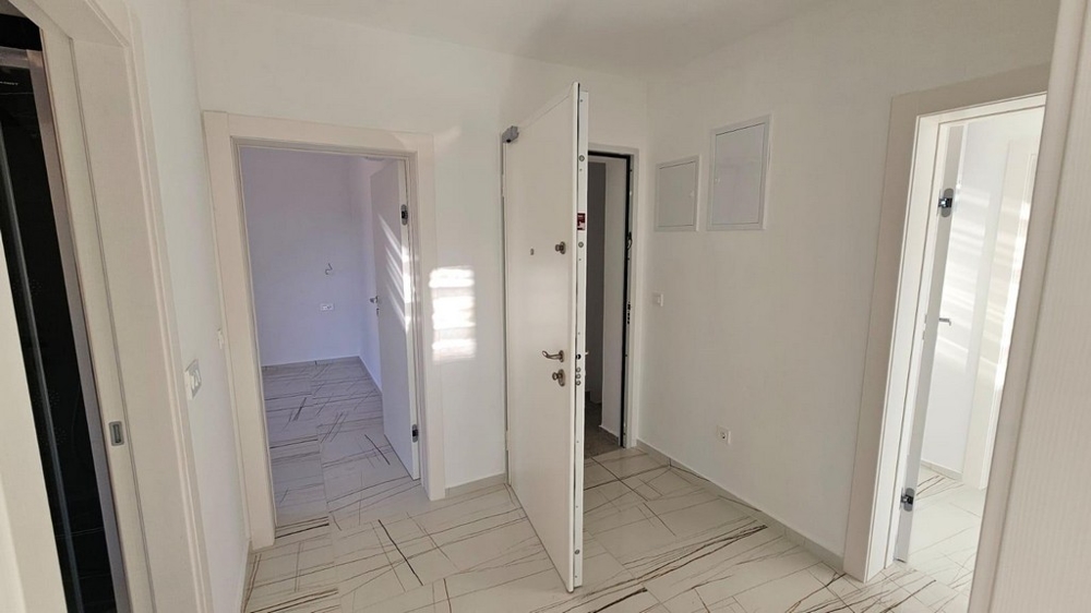 Couloir avec porte d'entrée blanche et accès à d'autres pièces