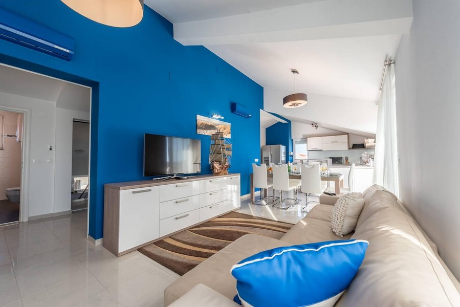 Séjour avec mur bleu et cuisine ouverte
