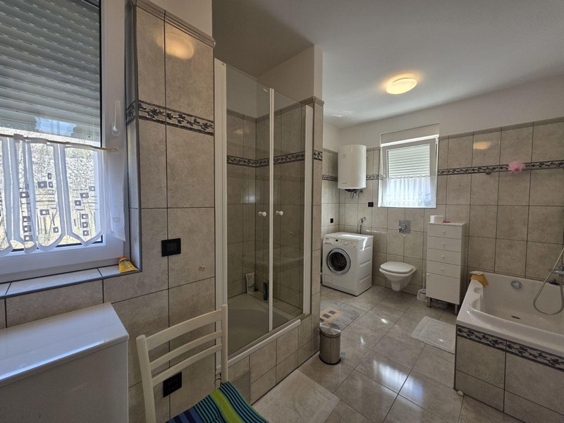 Grande salle de bains avec douche, baignoire et lave-linge