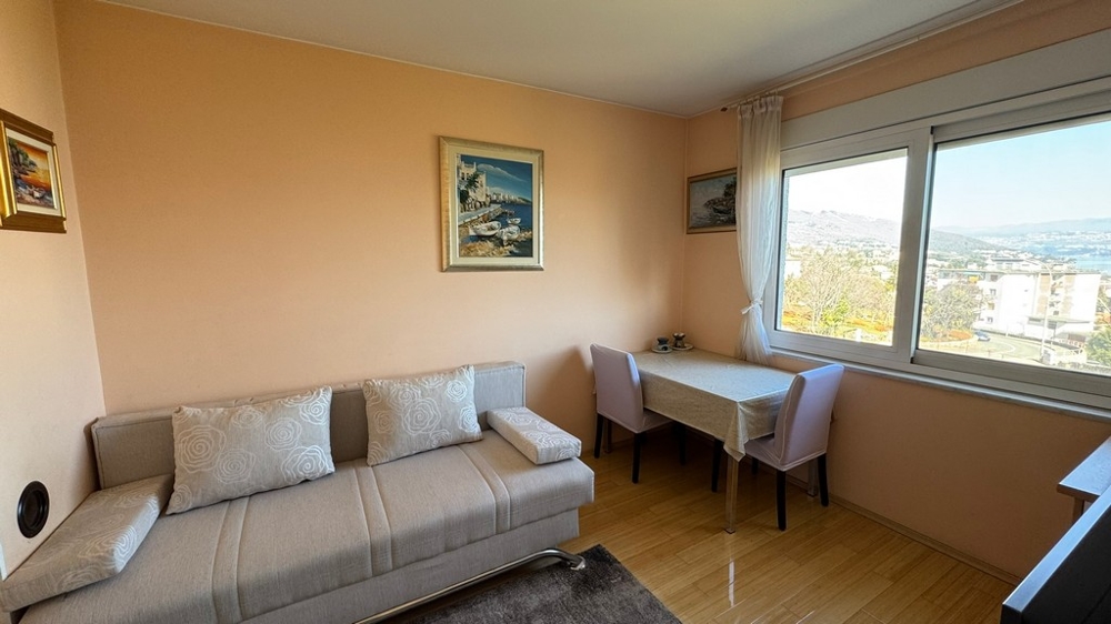 Séjour avec canapé, table et grande fenêtre avec vue mer