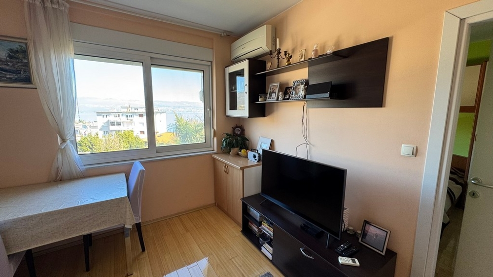 Séjour avec TV, étagère et climatiseur au mur