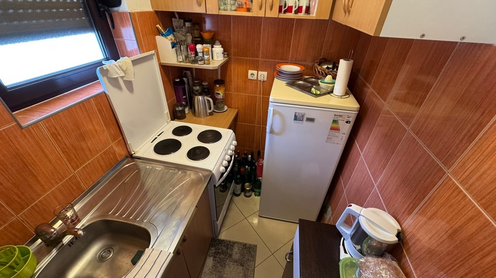 Petite cuisine avec cuisinière, évier et réfrigérateur