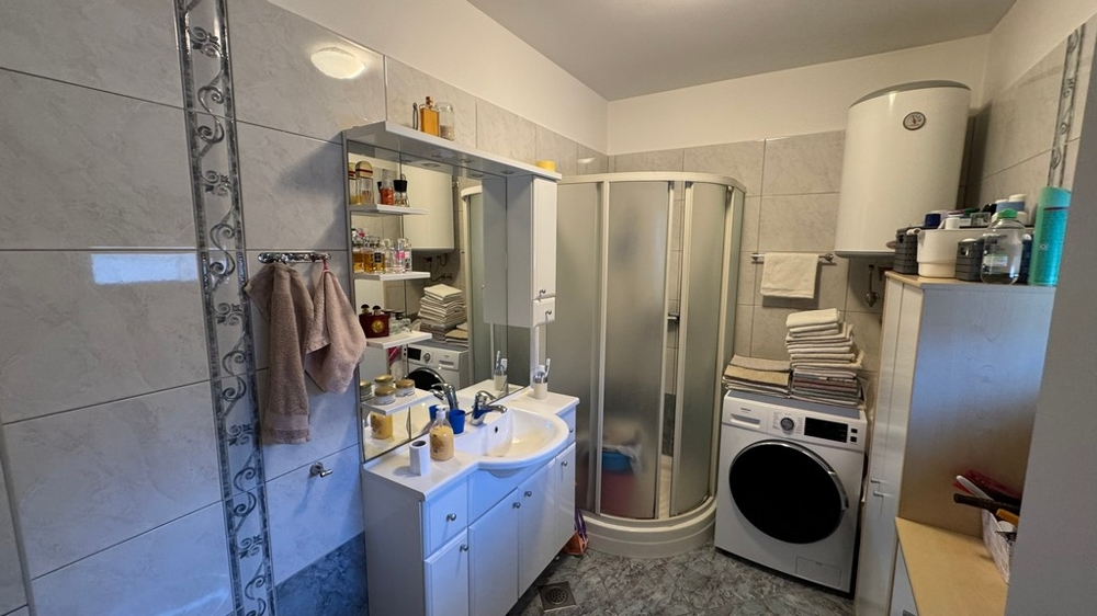 Salle de bains avec douche, lave-linge et lavabo avec miroir