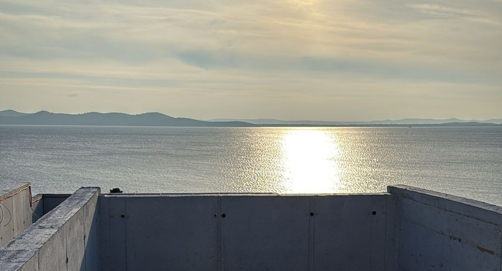 Reflet du soleil sur l'eau derrière le garde-corps en béton