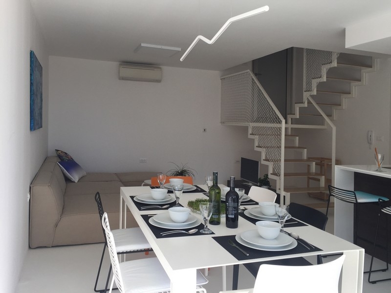 Séjour avec canapé, coin repas et escalier vers la galerie