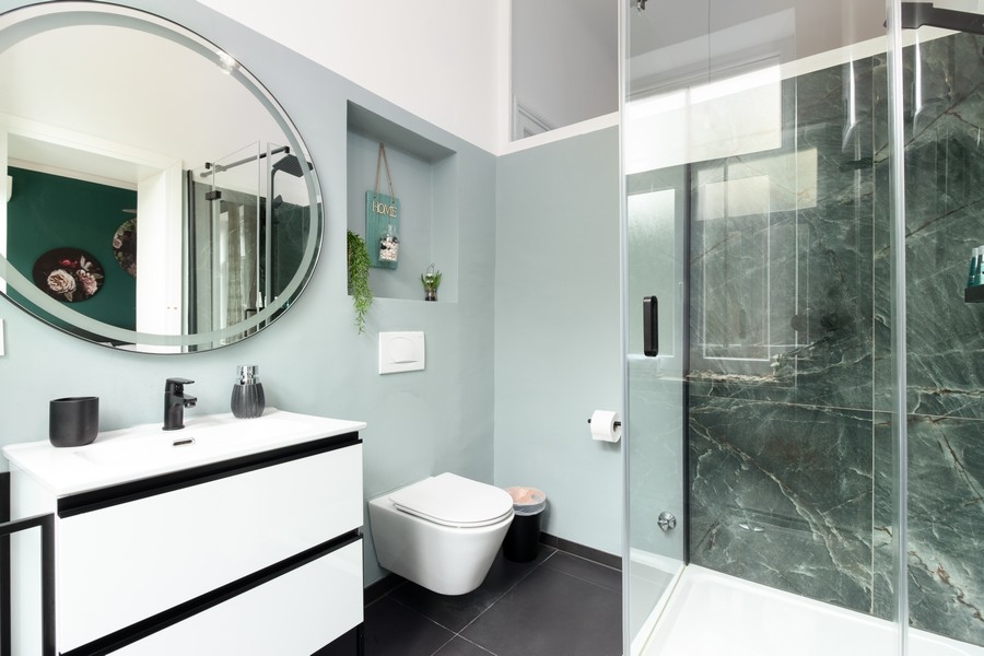 Salle de bains avec miroir rond et douche en verre