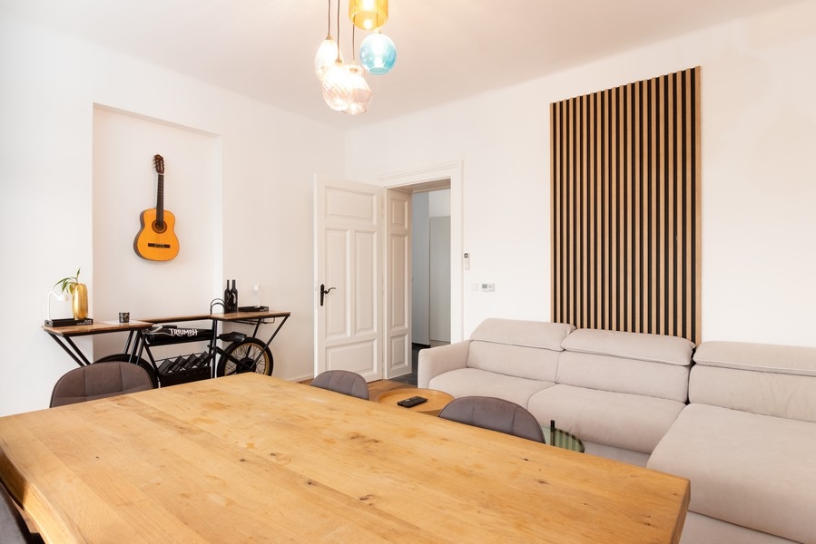 Séjour avec canapé, table en bois et revêtement mural