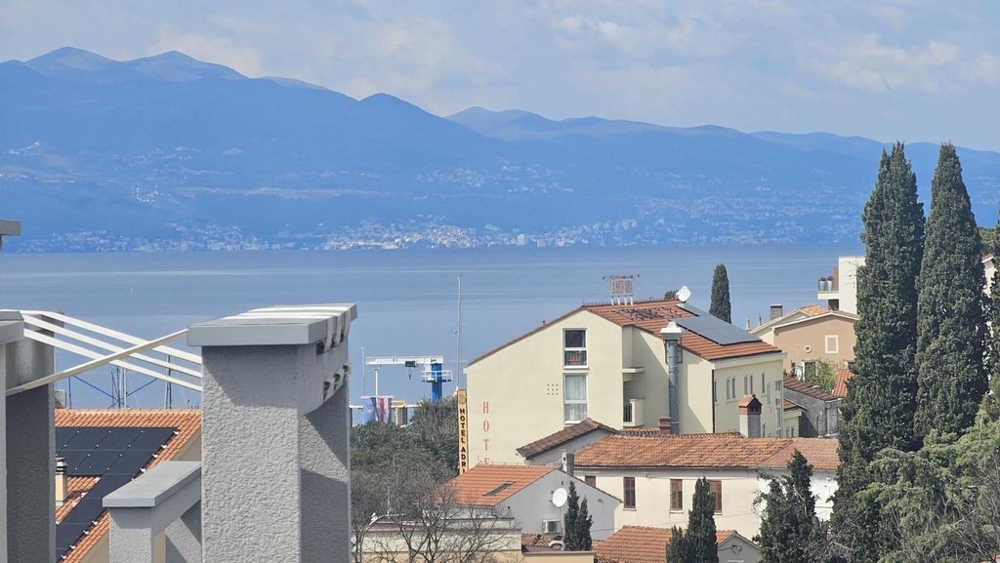 Vue par-dessus les toits et les cyprès sur la mer et la chaîne de montagnes