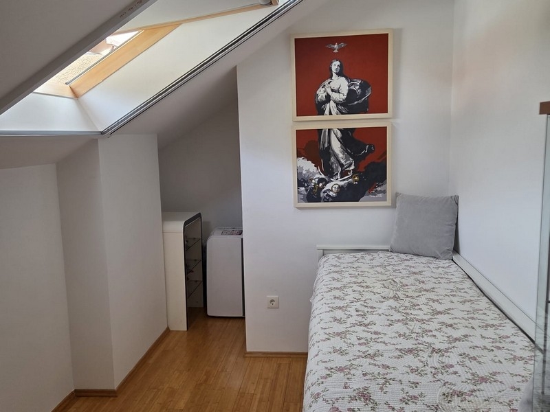 Chambre d'amis avec lit simple et fenêtre de toit
