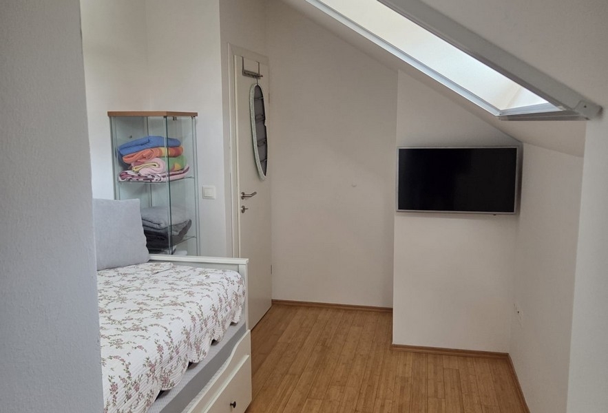 Chambre d'amis avec lit, TV et toit en pente