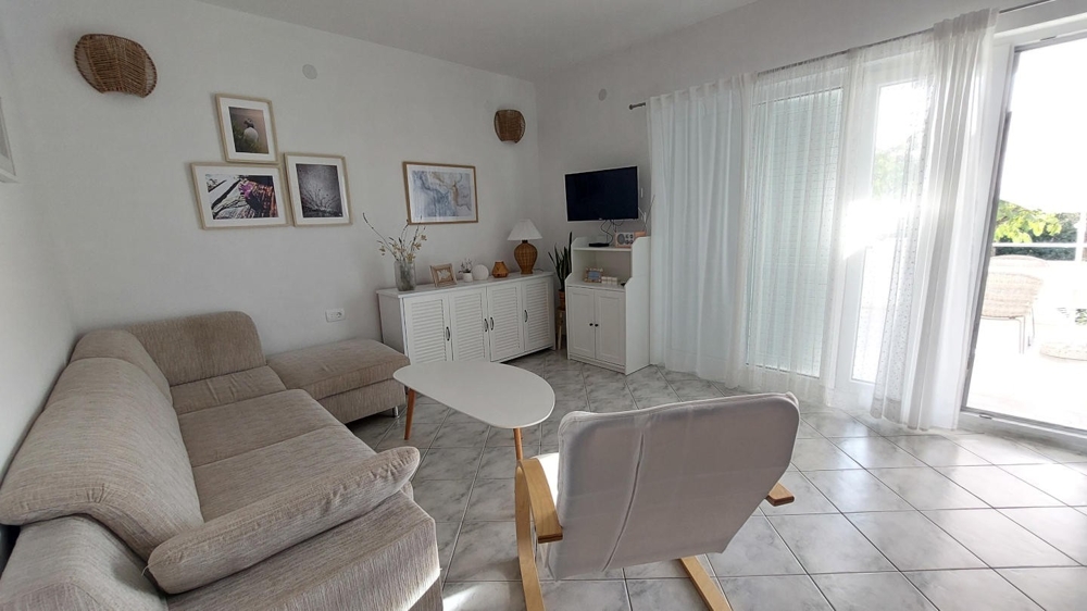 Séjour lumineux avec canapé, fauteuil et accès à la terrasse