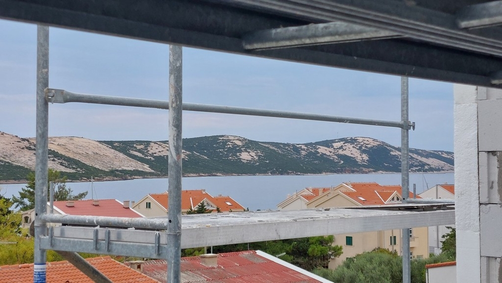 Vue à travers l'échafaudage sur les toits, la baie et le versant karstique