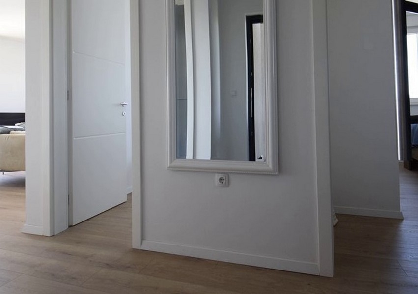 Couloir avec miroir mural et porte de pièce ouverte