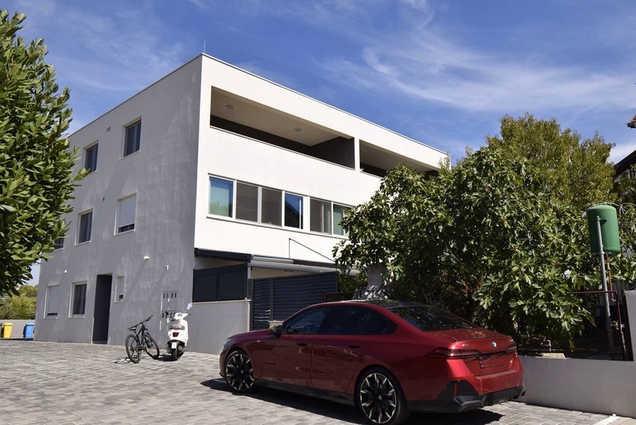 Immeuble d'habitation avec loggia à l'étage et places de stationnement devant
