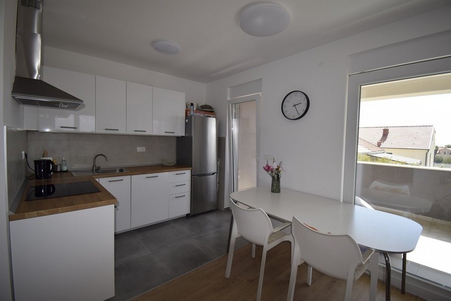 Cuisine équipée avec table à manger et porte-fenêtre vers le balcon