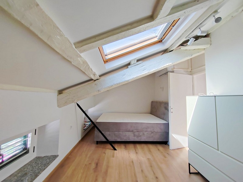 Deuxième chambre sous les combles avec lit et poutres de toit