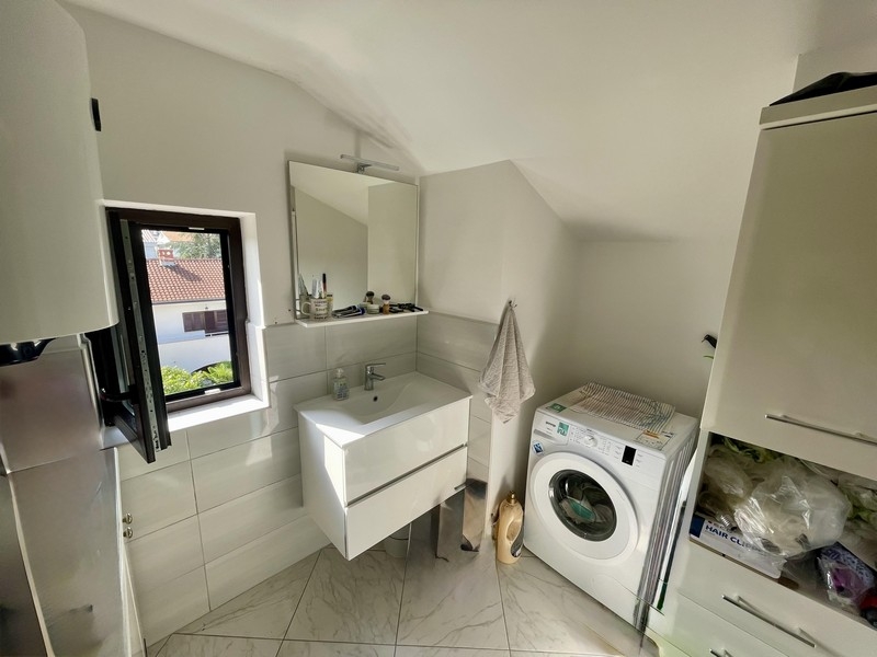 Salle de bains avec lave-linge et fenêtre