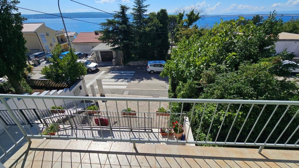 Balcon avec pots de fleurs et vue par-dessus la rue jusqu'à la mer