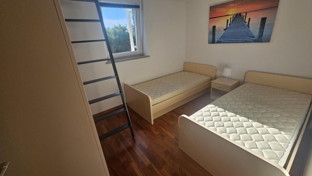 Chambre d'enfants ou d'amis avec deux lits simples et échelle vers la galerie