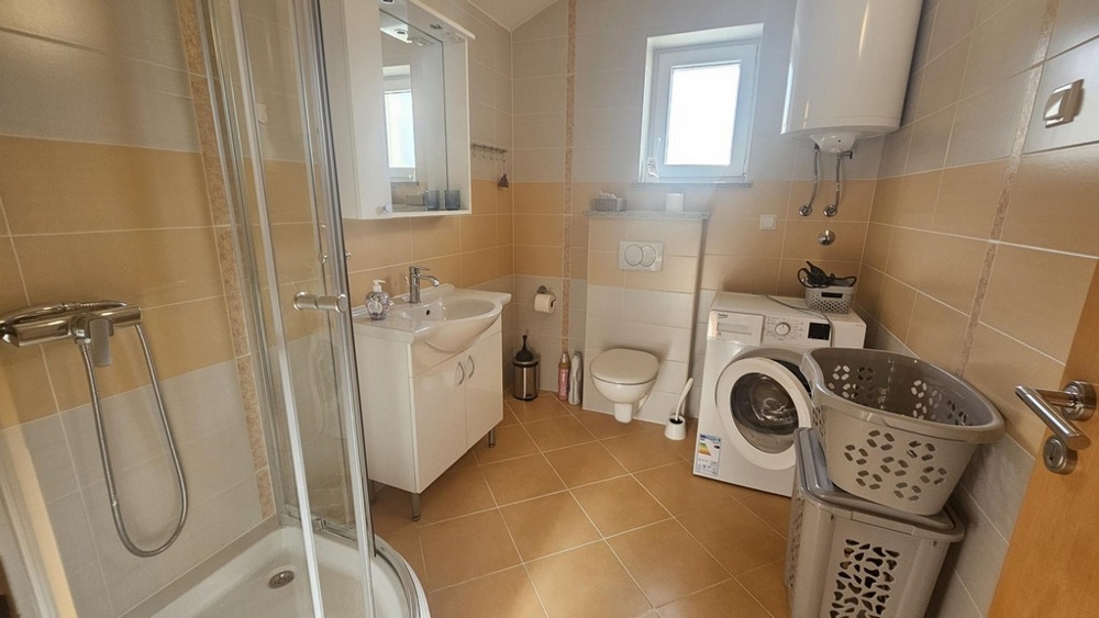 Salle de bains avec douche, lave-linge et fenêtre