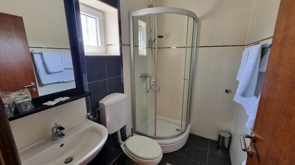 Salle de bains avec carrelage foncé et douche.
