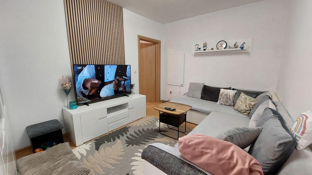 Séjour lumineux avec grand canapé et TV