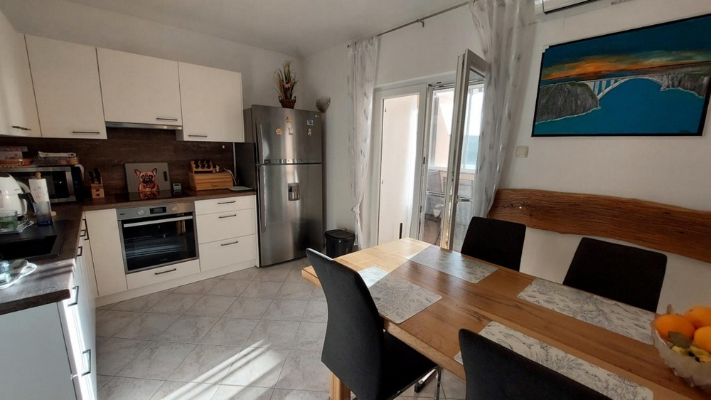 Cuisine avec table à manger et porte donnant sur la loggia