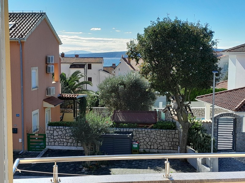 Vue par-dessus un olivier et les maisons voisines sur la mer