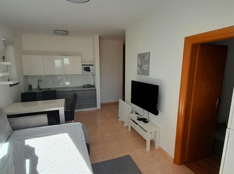 Séjour avec télévision, table à manger et accès à la chambre