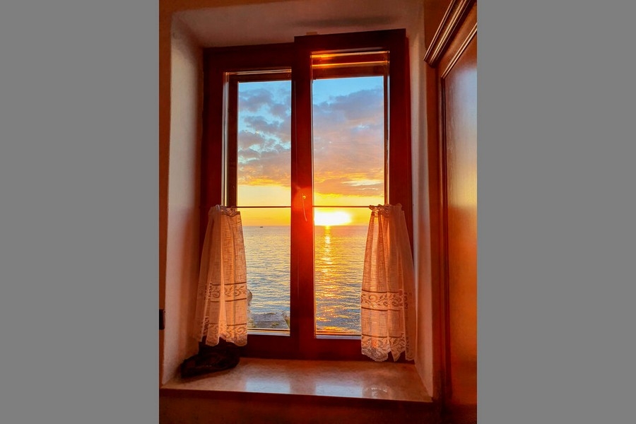 Coucher de soleil sur la mer derrière la fenêtre à petits carreaux