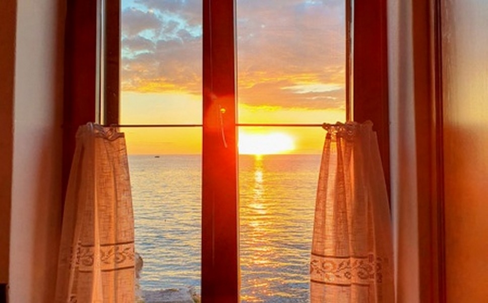 Soleil du soir sur la mer derrière la fenêtre en bois