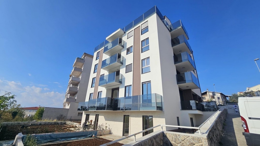 Immeuble neuf à plusieurs étages avec balcons vitrés à flanc de colline