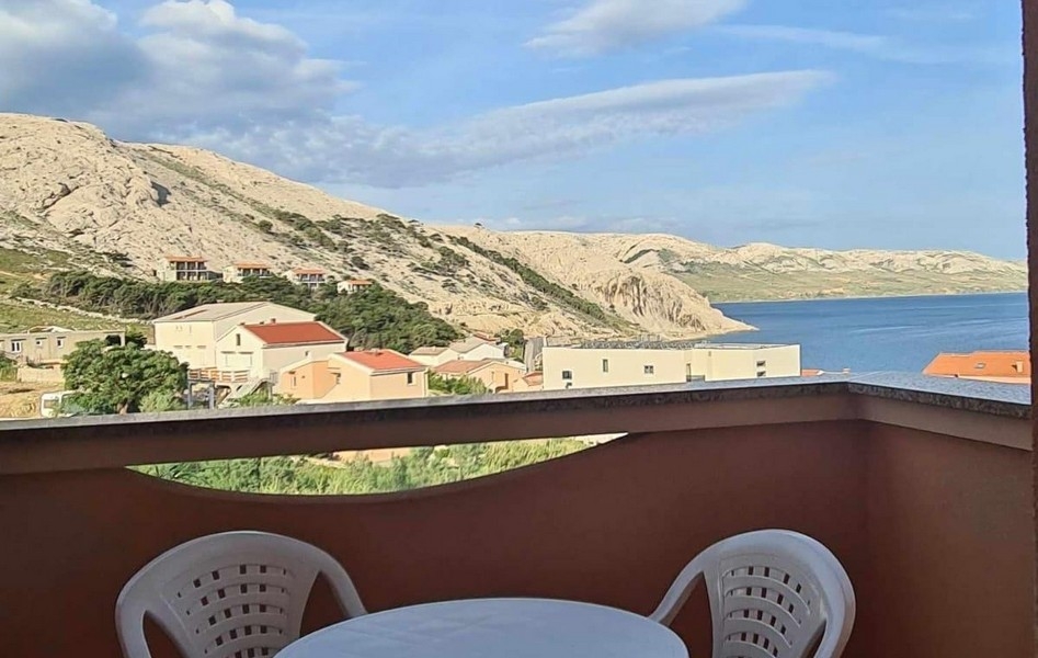 Balcon avec chaises blanches et vue sur le versant karstique et la mer