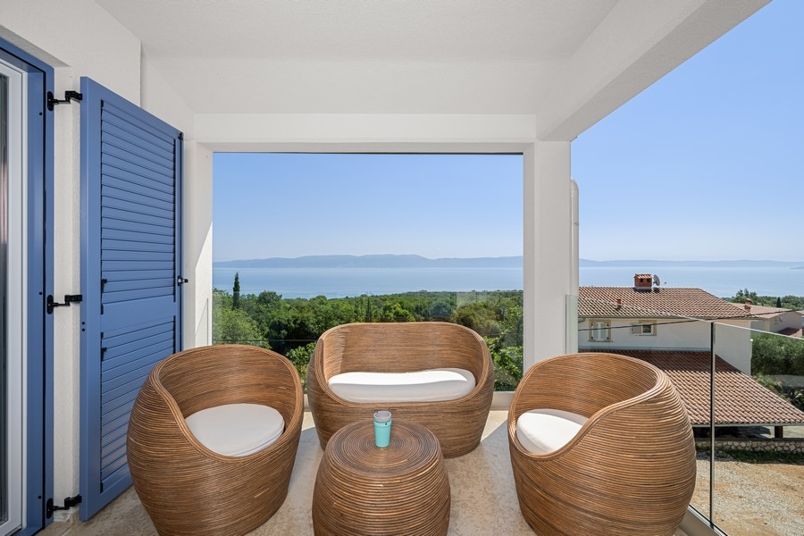 Loggia avec meubles en rotin et volets bleus au-dessus de la baie