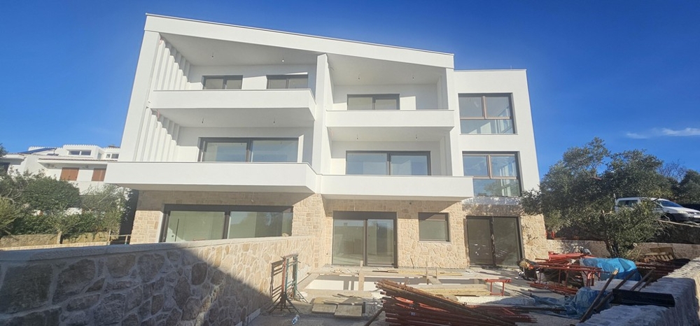 Immeuble neuf avec balcons et soubassement en pierre naturelle sous un ciel bleu