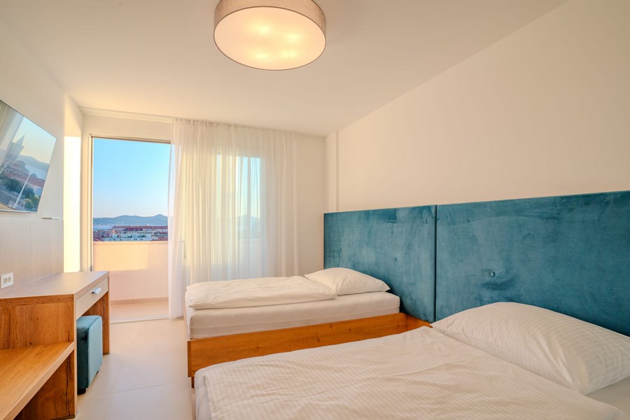 Chambre avec deux lits et accès au balcon