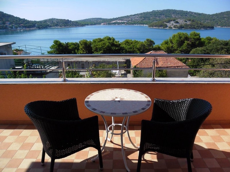 Balcon avec table ronde et deux fauteuils en osier au-dessus de l'eau
