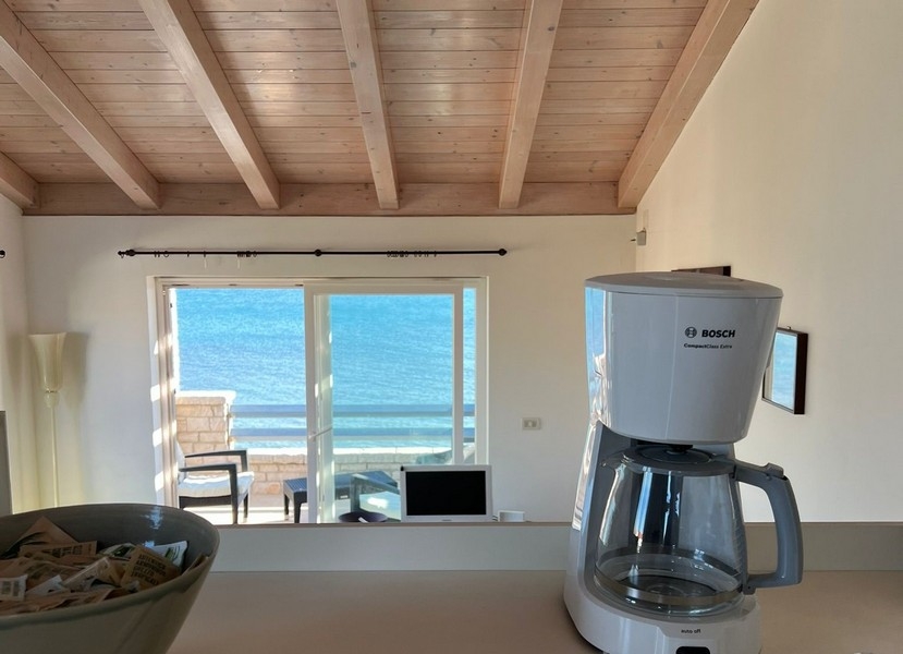 Vue de la cuisine, à travers le séjour, sur la terrasse et la mer