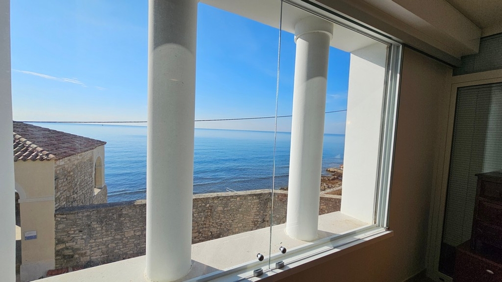 Vue par la fenêtre d'angle sur le mur du quai et la mer