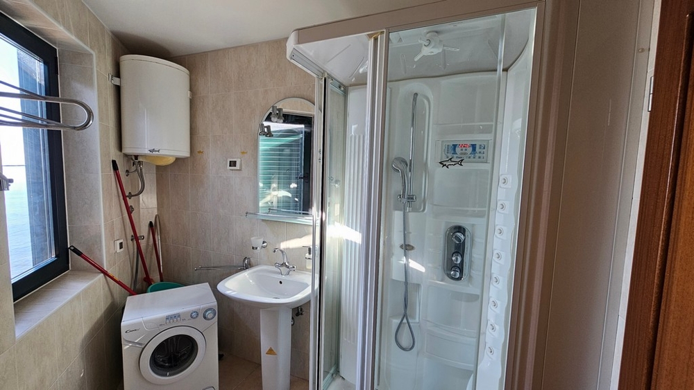 Salle de bains avec douche, lave-linge et fenêtre
