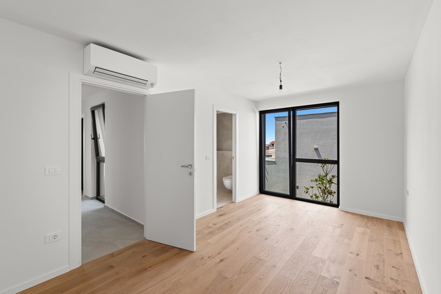 Chambre avec parquet et grande fenêtre
