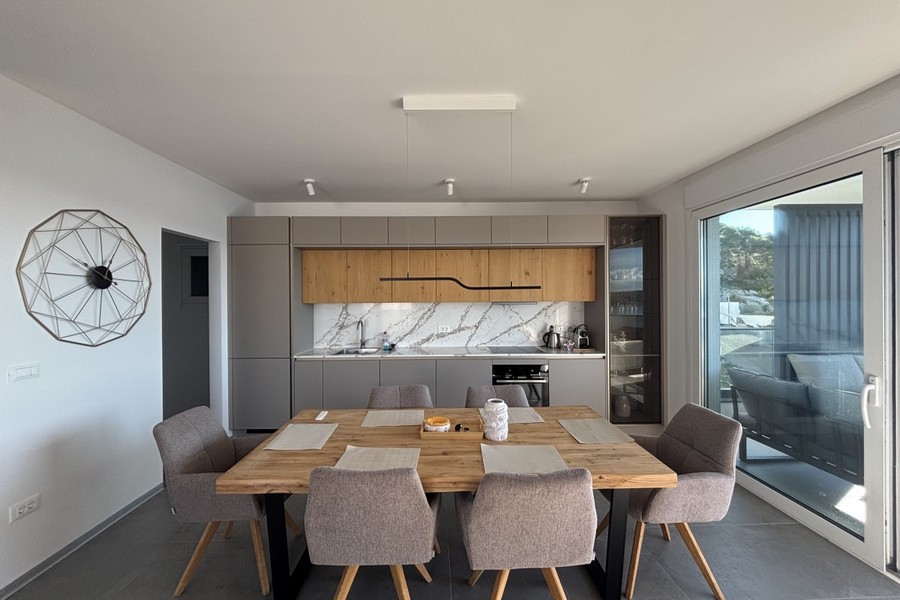 Cuisine équipée moderne avec coin repas et grande baie vitrée
