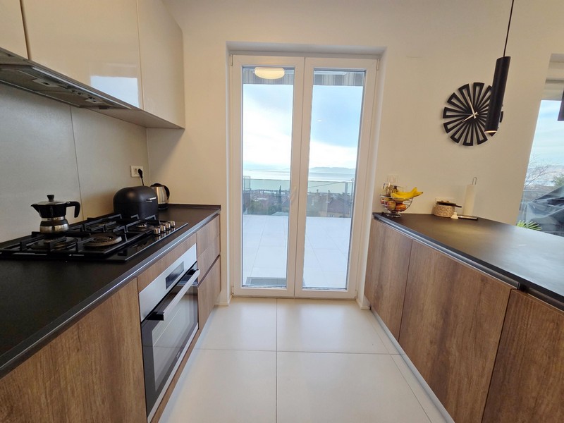 Cuisine linéaire avec cuisinière à gaz et porte de la terrasse