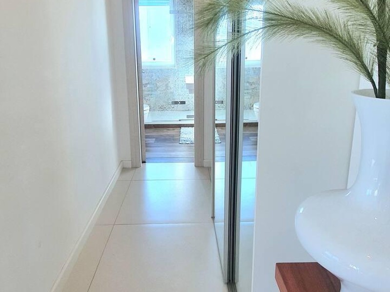 Couloir clair avec armoire à miroir et vue sur la salle de bains