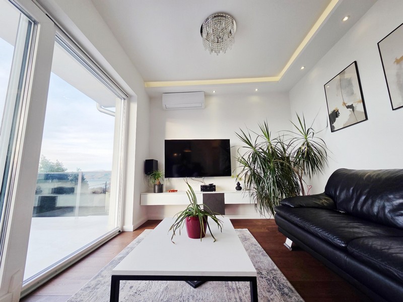 Salon avec canapé en cuir noir et fenêtre du sol au plafond