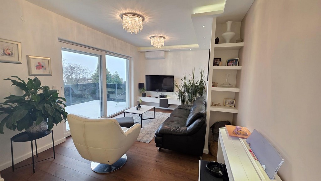 Salon avec téléviseur, étagère et fauteuil pivotant blanc