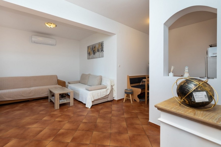 Séjour de l'appartement avec sièges et passage vers la cuisine
