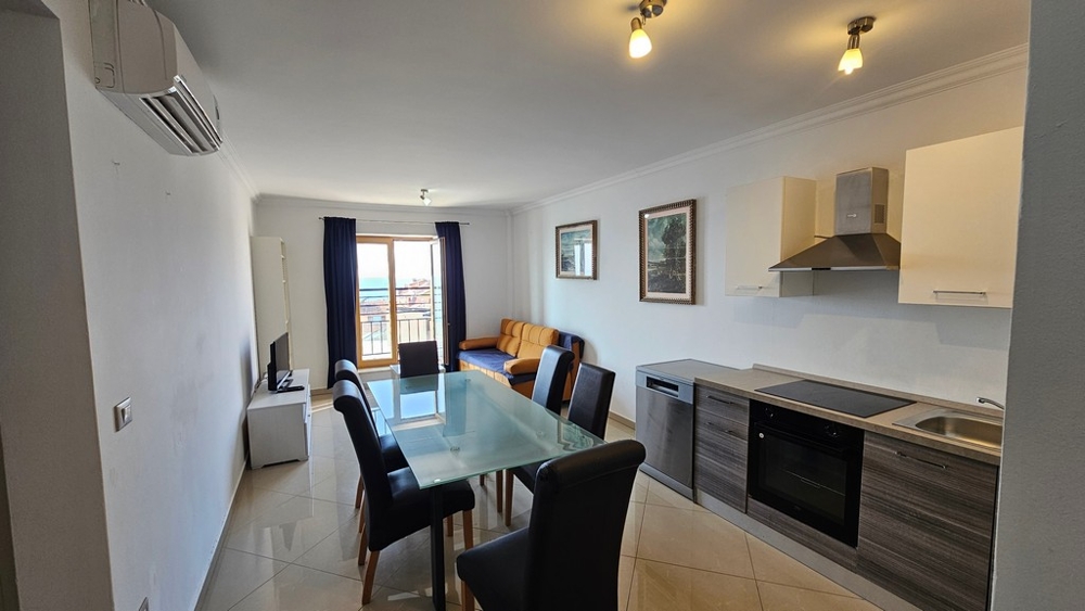 Salon clair avec cuisine ouverte, coin repas et vue sur la mer