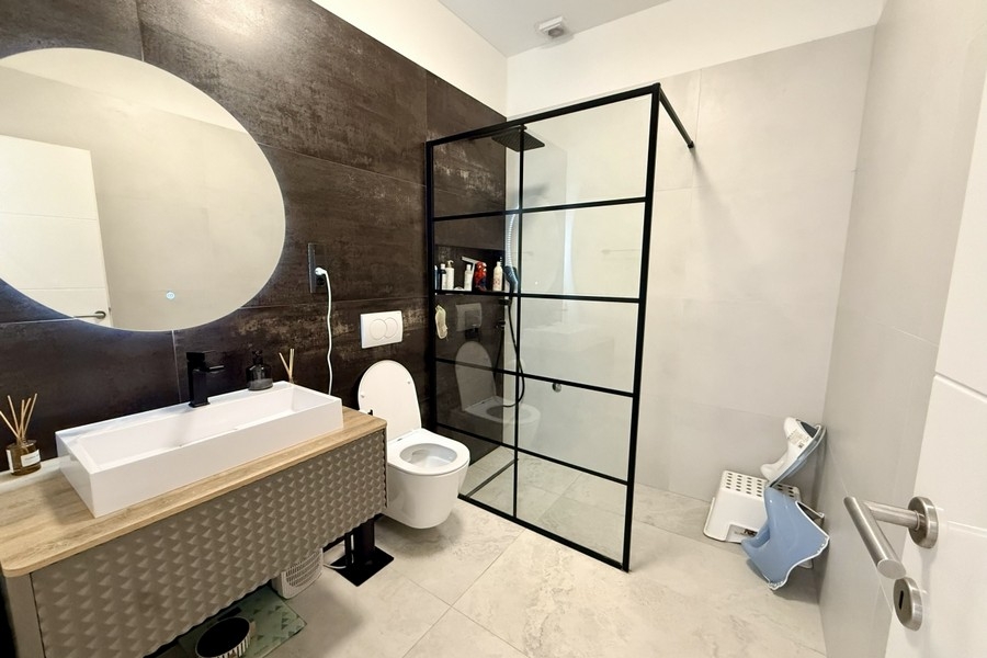 Salle de bains à l'équipement élégant avec cabine de douche en verre
