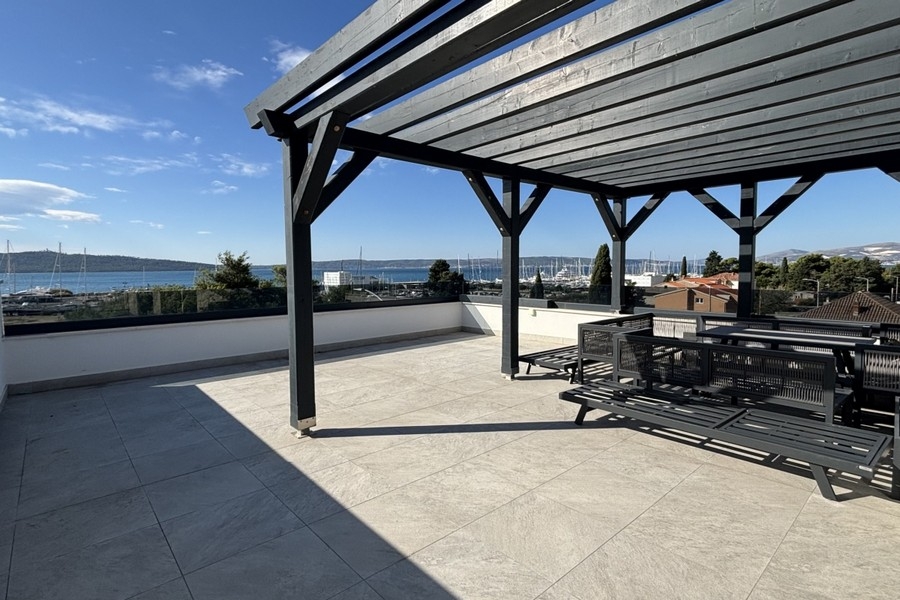 Toit-terrasse sous une pergola en bois foncé avec vue sur le port
